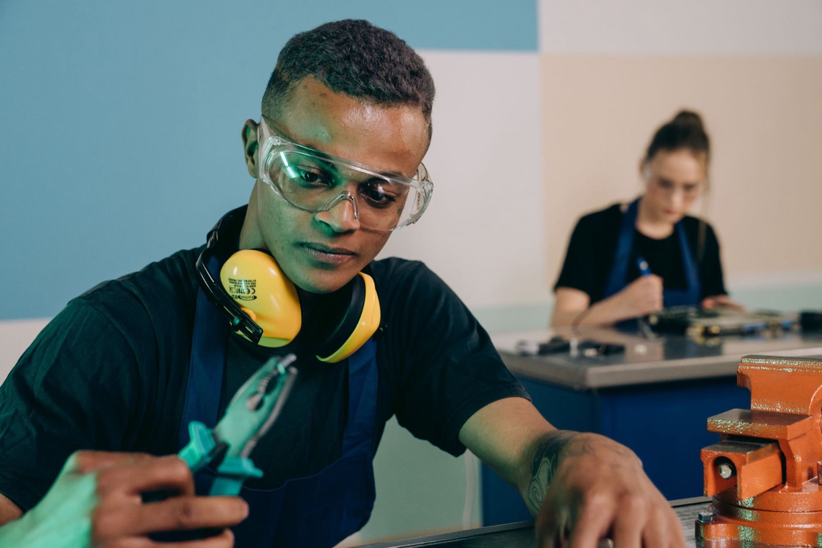 Young technician in safety goggles working at a bench
