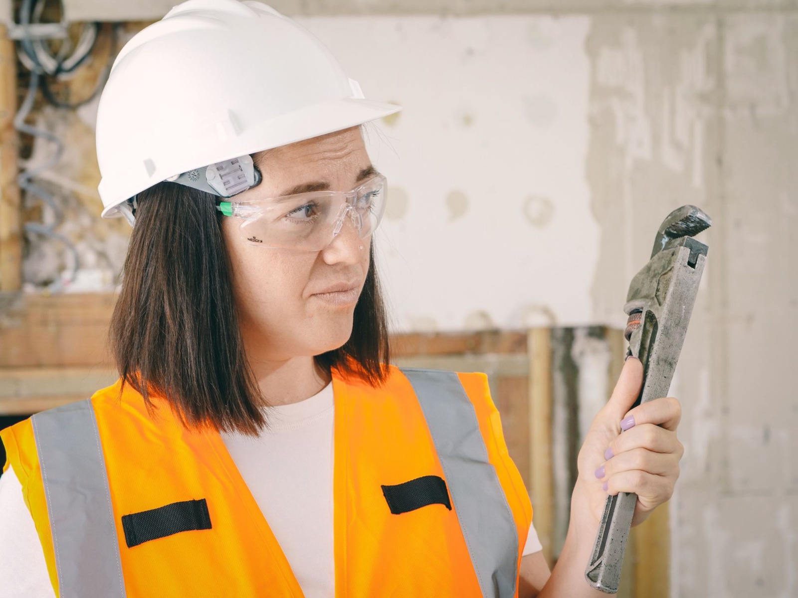 Facilities engineer in a hard hat inspecting a pipe wrench